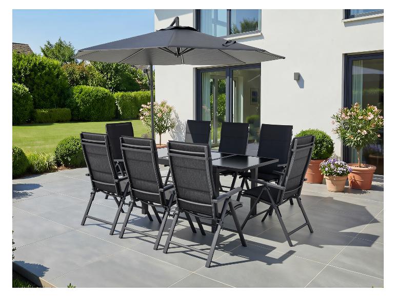 Gartenmöbel-Set mit Sonnenschirm auf einer Terrasse, umgeben von Grün und Blumen.