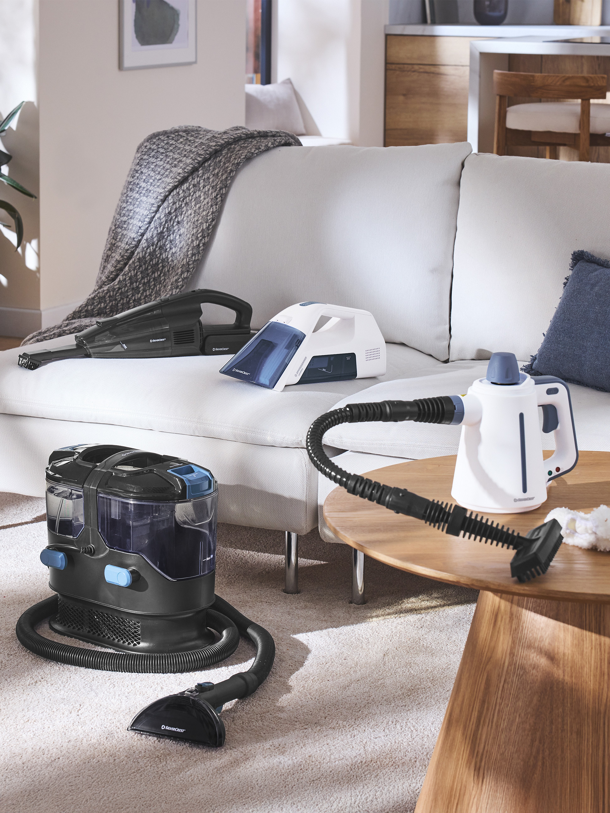 Staubsauger und Dampfreiniger in einem modernen Wohnzimmer mit Sofa und Couchtisch.