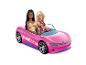 Zwei Puppen in einem pinken Spielzeug-Cabrio mit weißem und blauem Streifen.