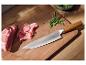 Kochmesser mit Holzgriff, Schinken und Rucola auf einem Holzschneidebrett.