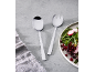 Salatbesteck-Set aus Edelstahl neben einem Teller mit frischem Salat.
