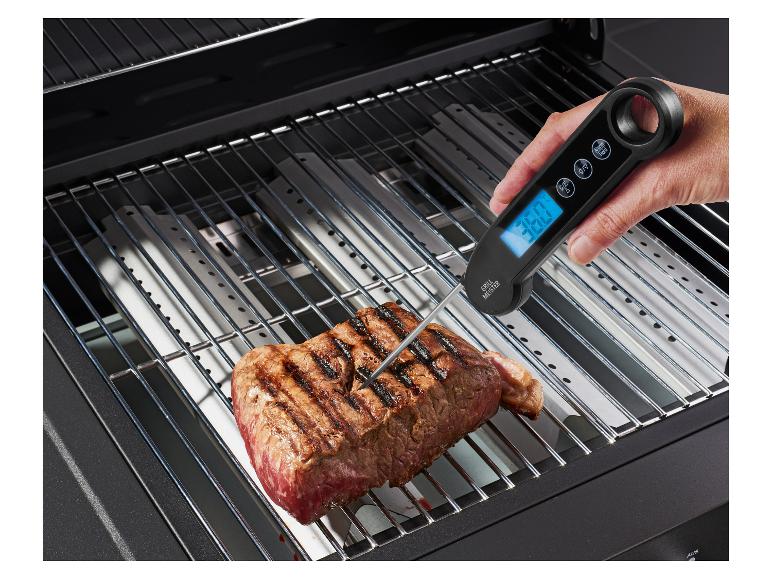 Digitales Grill Meister Fleischthermometer, das die Temperatur eines Steaks auf dem Grill überprüft.