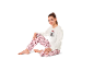 Mädchen in langärmeligem Pyjama mit Cartoon-Muster, auf dem Boden sitzend.