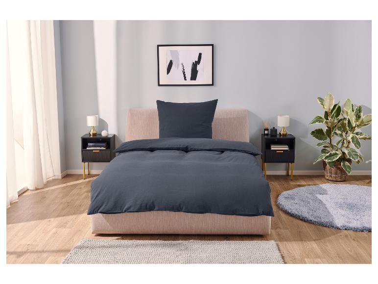 Dunkelblaue Bettwäsche und weicher Teppich in einem modernen Schlafzimmer.