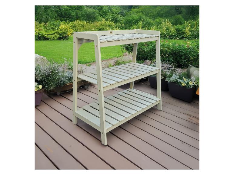 Grüne Pflanzenbank mit drei Regalböden auf einer Holzterrasse, umgeben von Grünpflanzen.