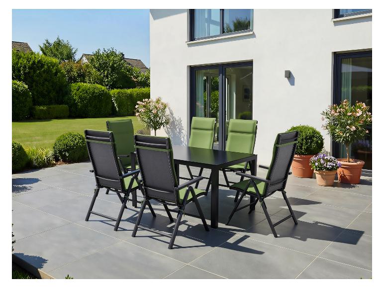 Gartensitzgruppe mit schwarzem Tisch und grünen Stühlen auf einer Terrasse neben einem modernen Haus.