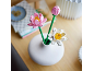 Rosa und weiße Spielzeug-Lotusblumen in einer weißen Vase auf einem Holztisch.