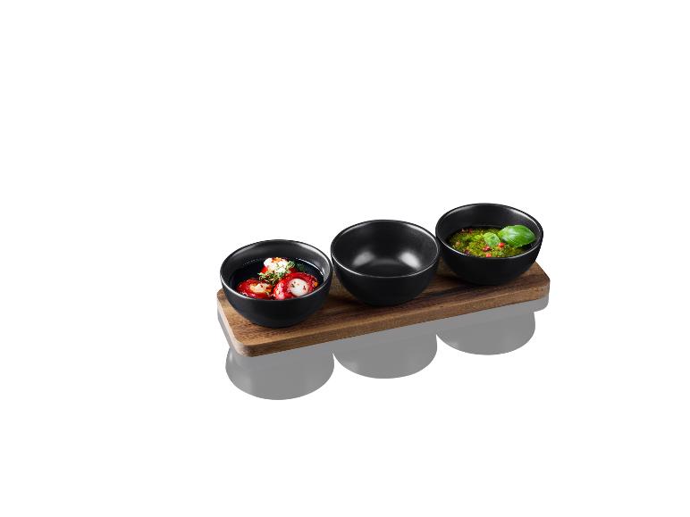 Set aus drei schwarzen Schalen mit Saucen und gefüllten Paprika auf Holzsockel.