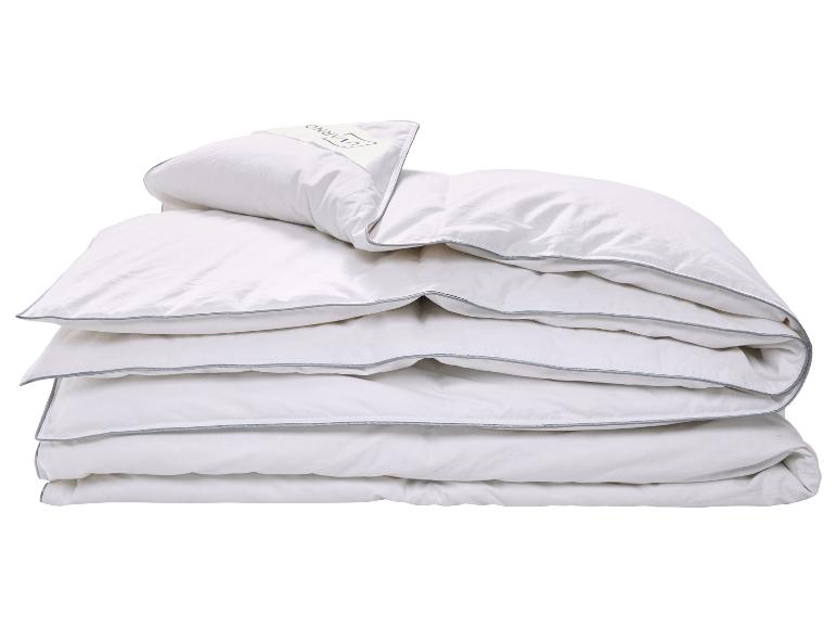 Weiße Bettdecke und Kissen mit grauem Rand, gefaltet und gestapelt.