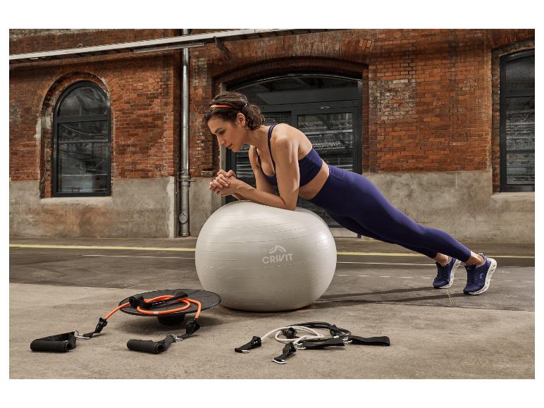 Eine Frau in CRIVIT Sportschuhen und Sportkleidung macht Unterarmstütz auf einem Gymnastikball.