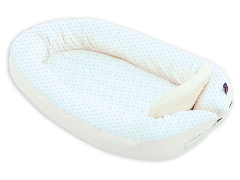 Ein Baby-Nestchen mit einem weiß-grünen Muster.