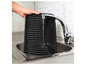 Eine schwarze Grillplatte wird unter dem Wasserhahn abgewaschen.