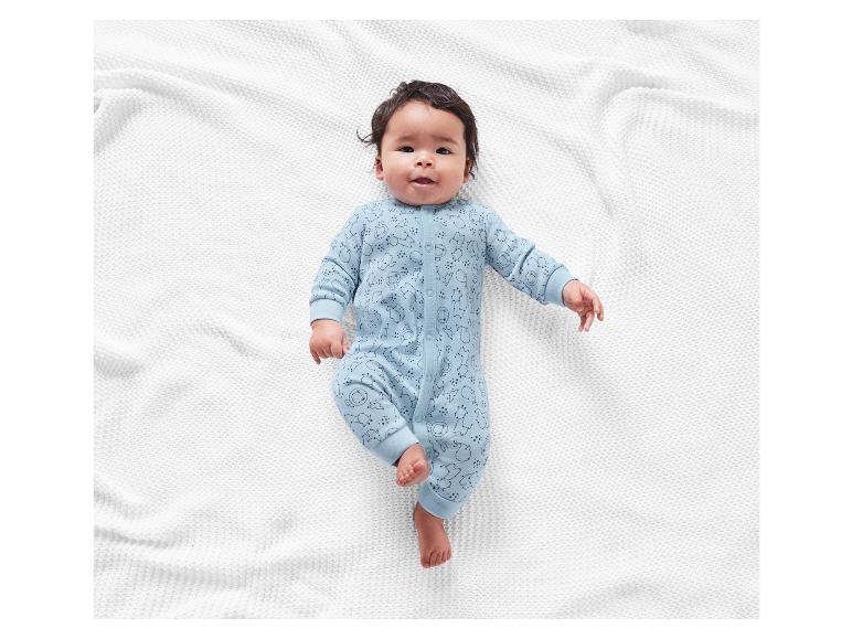 Baby in hellblauem Strampler mit Tiermotiv.