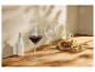 Rotwein- und leere Gläser, mit Trauben, Käse und Olivenöl auf einem Holztisch.