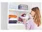 Frau räumt ein Tefal Bügeleisen und Kleidung in einen Schrank.