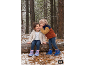 Kinder in Winterkleidung und Stiefeln spielen im verschneiten Wald.