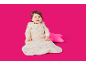 Lächelndes Baby im Schlafsack mit Hasen- und Mondmuster, neben einem rosa Sternenkissen.