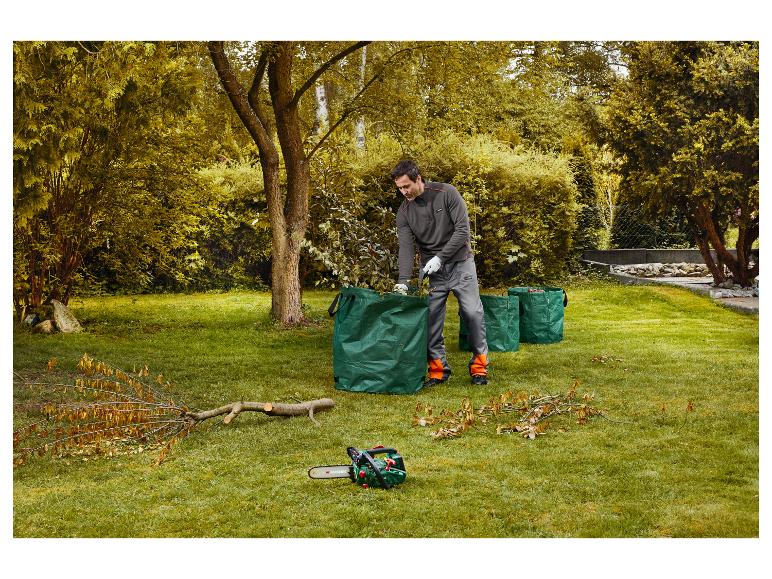 Mann räumt Äste in grüne Gartensäcke, daneben liegt eine Kettensäge.