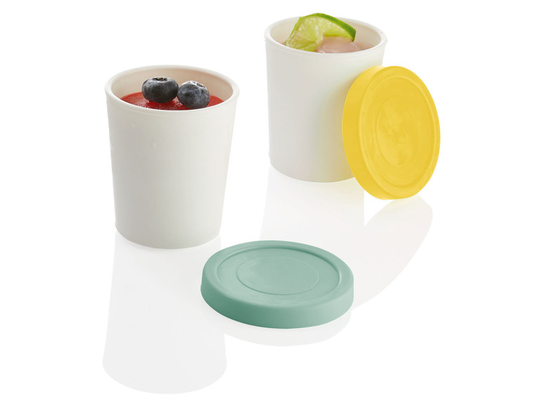 Zwei weiße Becher mit Deckeln, einer mit Blaubeeren, der andere mit einer Limette.