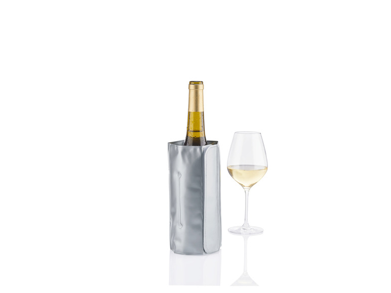 Eine Flasche Weißwein in einer Weinkühlung und ein Glas Weißwein daneben.