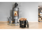 Moderner Holzofen mit brennendem Feuer, Kaminbesteck und Holzscheiteimer.