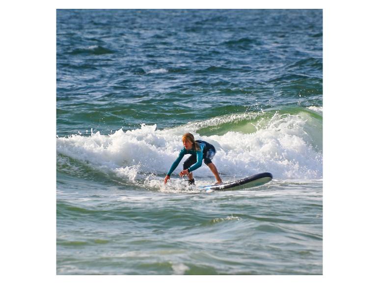 Ein Mädchen surft auf einer Welle.