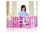 Ein Mädchen spielt mit einem pinken Puppenschrank voller Kleidung und Accessoires.