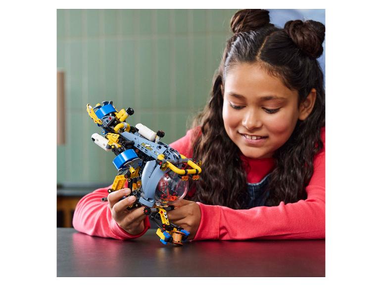 Ein lächelndes Mädchen hält ein gelb-blaues LEGO Technic U-Boot.