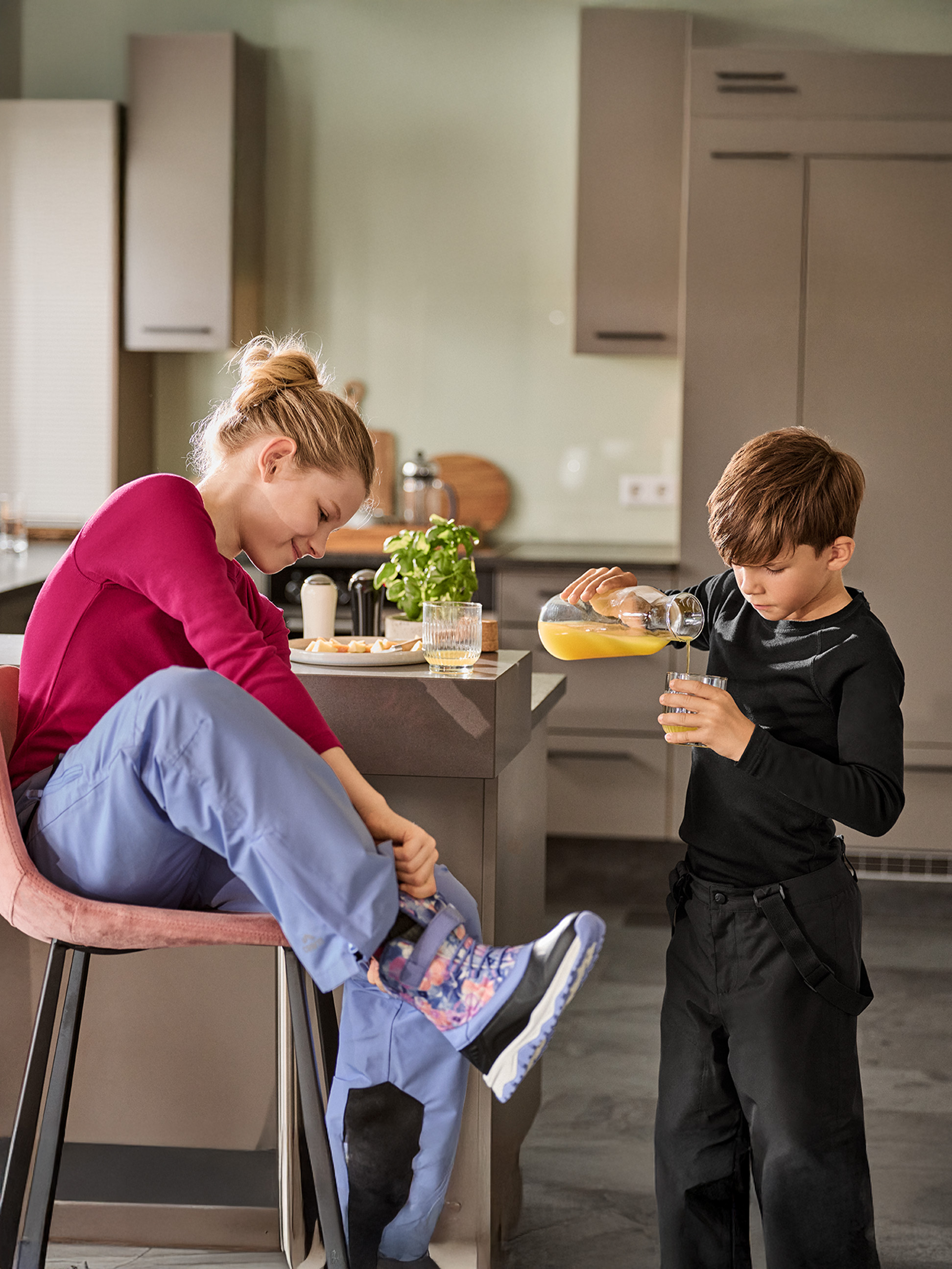 Frau und Kind in der Küche, bereit zum Ausgehen, mit Getränken und Snacks.