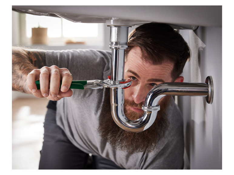 Ein Klempner repariert ein Waschbecken mit einer Zange.