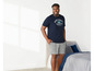 Mann in einem dunkelblauen T-Shirt mit Varsity-Druck und grauen Shorts.