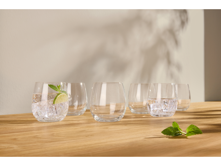 Gläser mit Wasser, Eis, Limette und Minze auf einer Holzoberfläche.