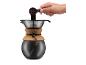 Hand gießt gemahlenen Kaffee in eine Pour-over-Kaffeemaschine mit Korkband.