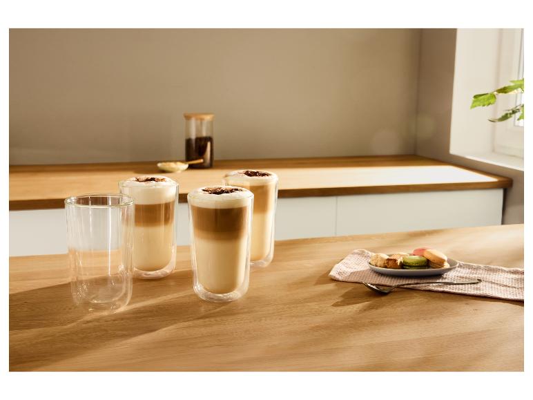 Drei Gläser Kaffee Latte mit Schaum und Schokoladenstreuseln, daneben Macarons und Kekse.