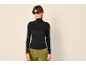 Frau in schwarzem Rollkragenpullover und grüner Hose, Sonnenbrille.