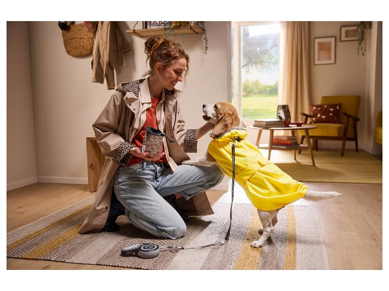 Frau und Hund im Regenmantel, mit Leckerlibeutel und Rollleine.