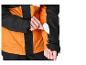 Eine Hand steckt eine weiße Karte in eine Reißverschlusstasche am Ärmel einer orange-schwarzen Jacke.