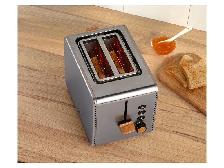 Edelstahl-Toaster mit Holzapplikationen, Toast und Marmelade auf einer Holztheke.