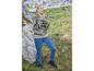 Eine Frau in einem gestreiften Pullover und blauen Jeans steht auf einer Wiese.