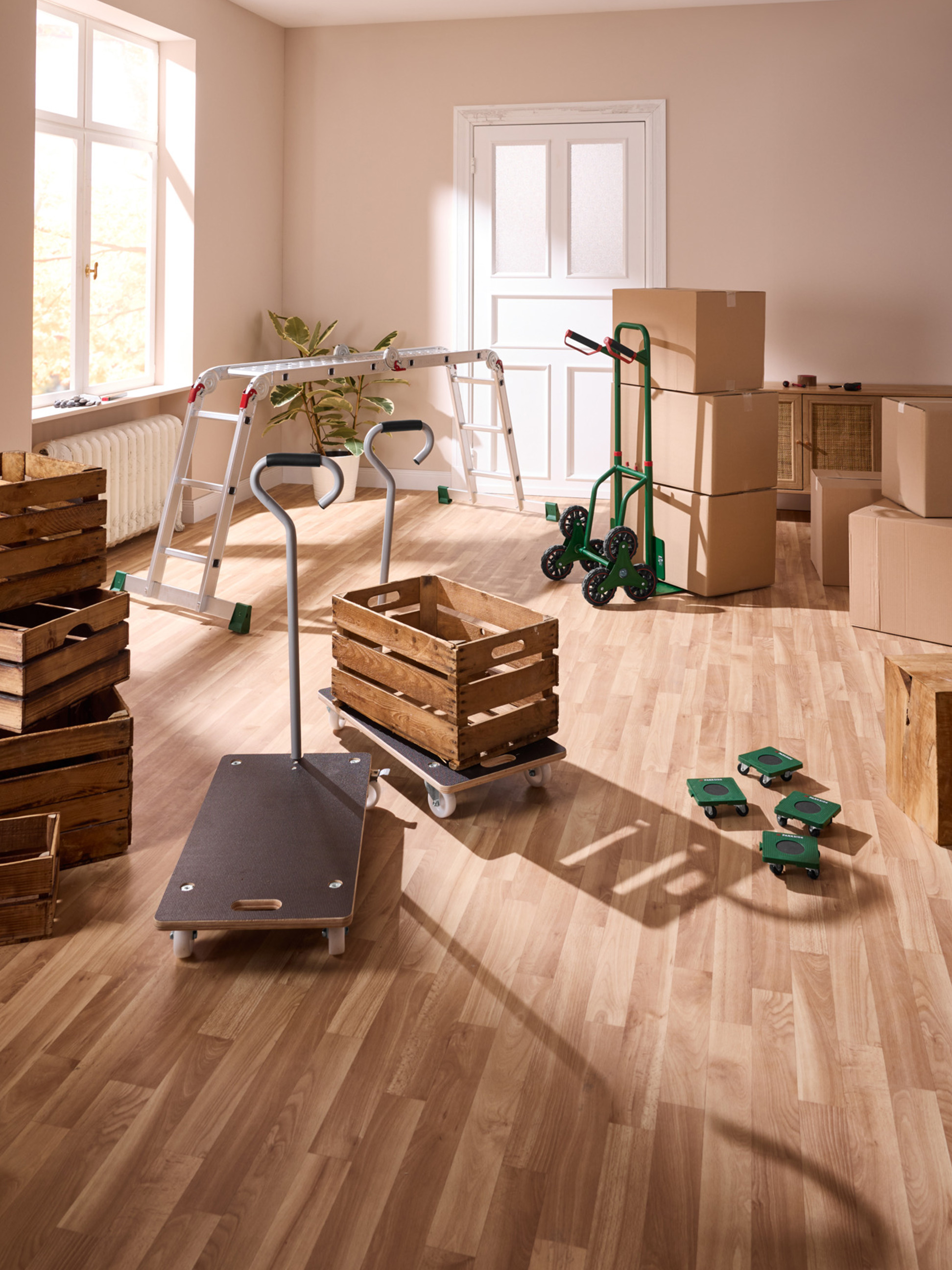 Transportwagen und Holzkisten in einem Raum mit Parkettboden, bereit für den Umzug.