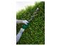 Heckenschere im Einsatz, schneidet eine grüne Hecke.