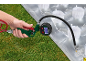 Hand hält eine Aufblaspistole mit Manometer, die eine transparente Luftmatratze auf Gras aufbläst.
