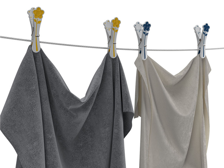 Zwei Handtücher hängen an einer Wäscheleine mit bunten Wäscheklammern.