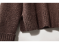 Nahaufnahme eines braunen Strickpullovers mit Rippbündchen und Seitenschlitz