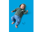 Baby in grünem Kapuzenpullover und blauer Hose, mit einer blauen Rassel.