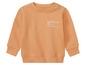Ein orangefarbener Baby-Pullover mit der Aufschrift 'future'.