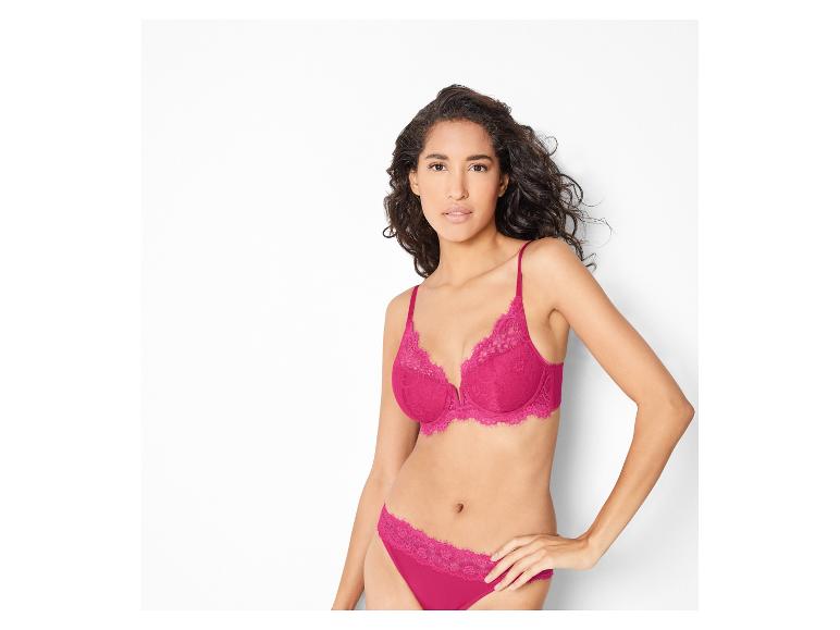 Eine Frau trägt einen rosafarbenen BH und Slip mit Spitze.