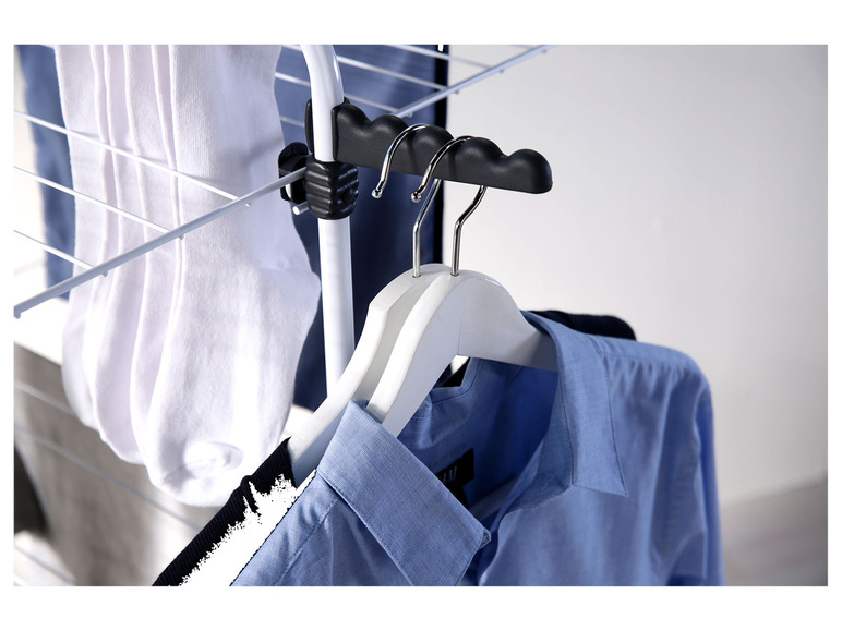 Socken und Hemden trocknen auf einem weißen Wäscheständer.