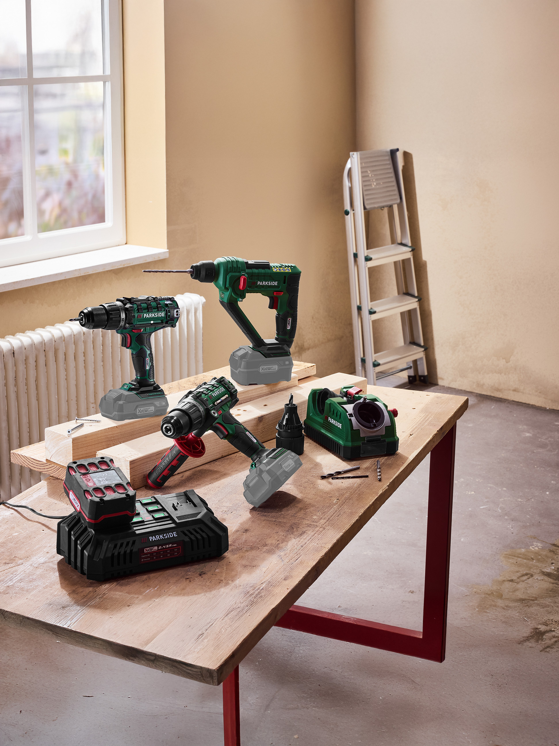 Elektrowerkzeuge, darunter Bohrmaschinen und ein Akkuladegerät, auf einem Holztisch.