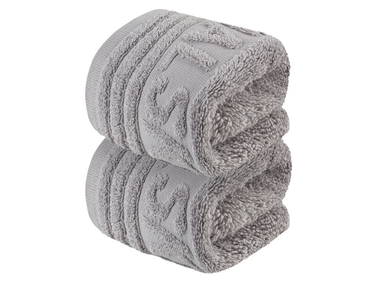 Zwei graue Handtücher, zusammengerollt.